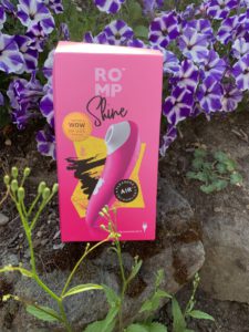 The box of the romp shine is pictured. It's bright pink with a photo of the toy that's inside box. The Romp Shine is an oral sex simulator sex toy. 
