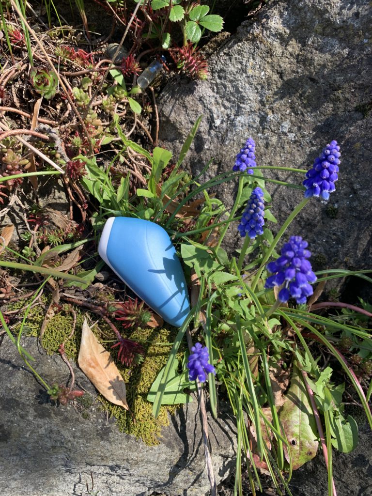 Satisfyer Love Breeze Pressure Wave Stimulator lays on a stone surrounded by lavender