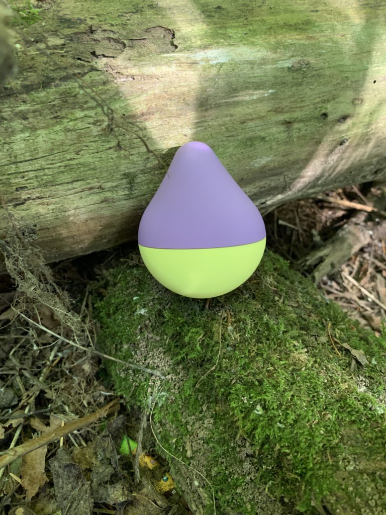 The iroha Mini vibrator in Fuji-Lemon sits on a mossy branch surrounded by trees. It's a compact vibrator that is battery-operated