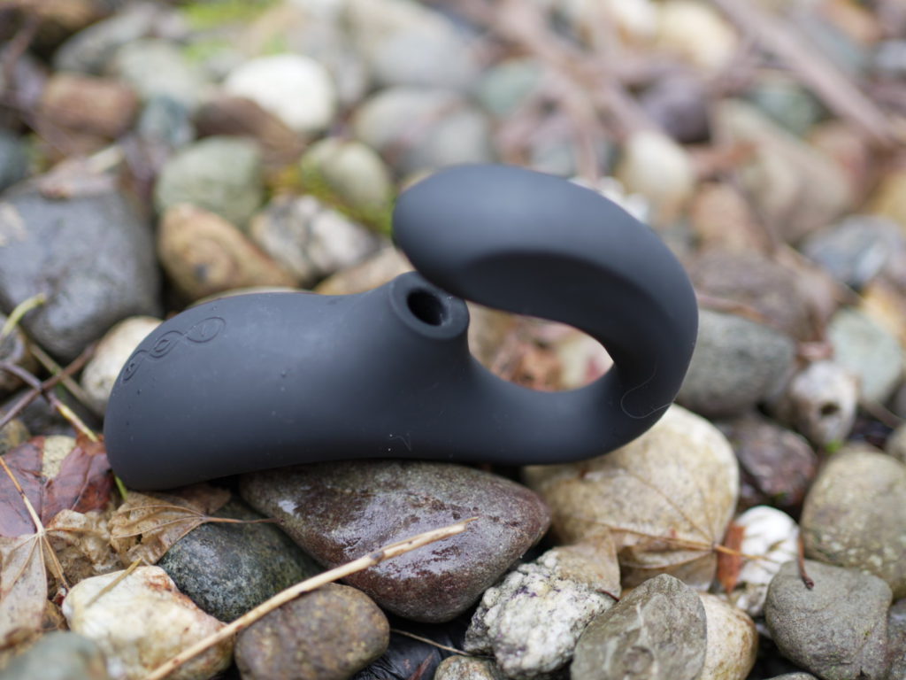 Lelo Enigma sits on a bed of stones with it's three control buttons displayed