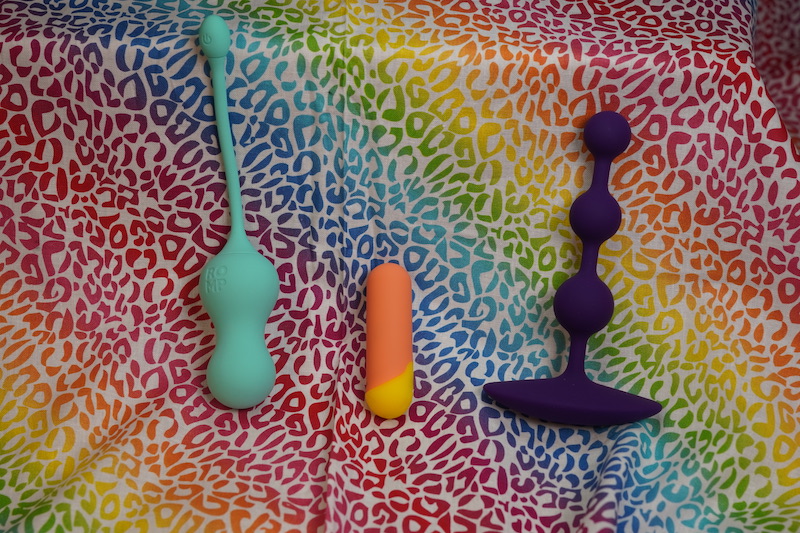 The ROMP Riot, Amp, and Cello are three toys in the ROMP line that came out most recently. Vibrating egg is on the left, the middle is the Riot, a bullet, and Amp is the purple anal beads
