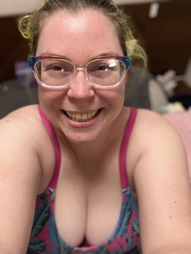 Rose is wearing a bright blue and pink bralette with a HUGE smile on her face. Her mental health has been suffering and she has been focusing on that but neglecting her body. Here she is, just back from a walk! 